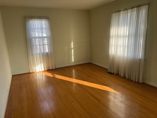 empty room with visible vents, light wood-style flooring, and baseboards