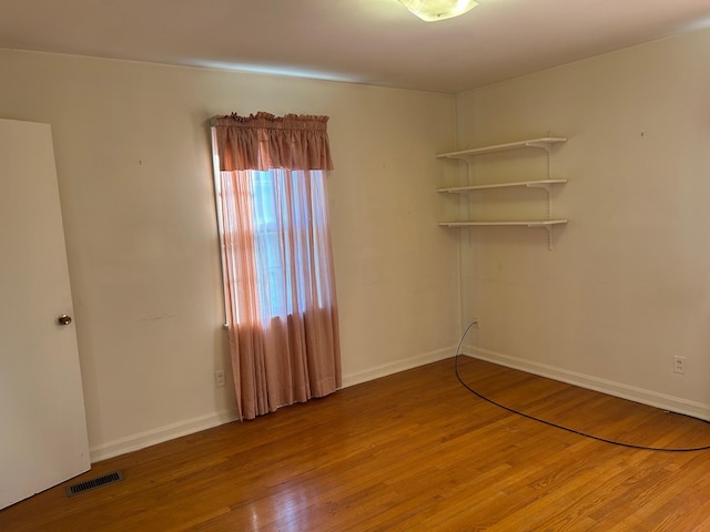 empty room featuring visible vents, baseboards, and wood finished floors