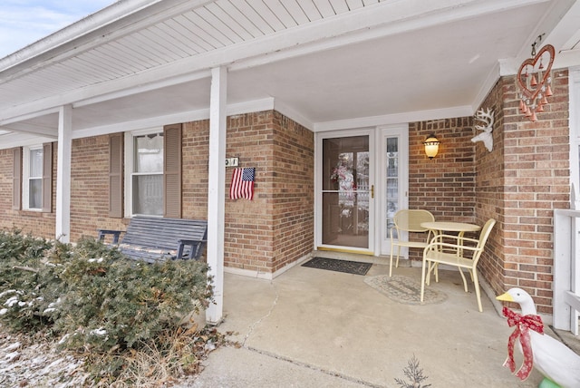 doorway to property featuring brick siding and a porch