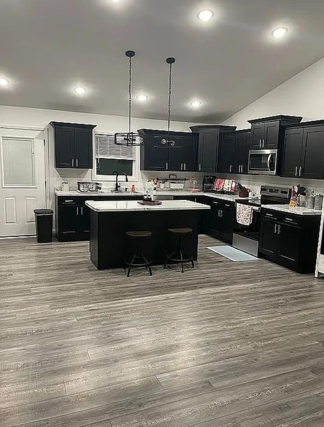 kitchen featuring stainless steel appliances, a center island, light countertops, and dark cabinetry