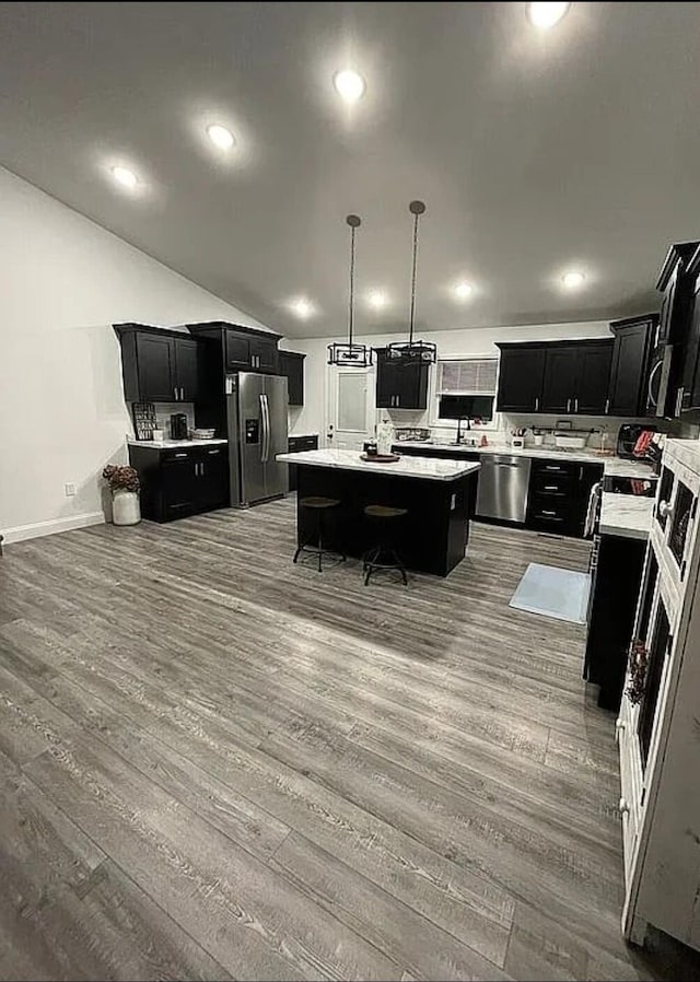 kitchen with a kitchen island, appliances with stainless steel finishes, light countertops, and dark cabinets