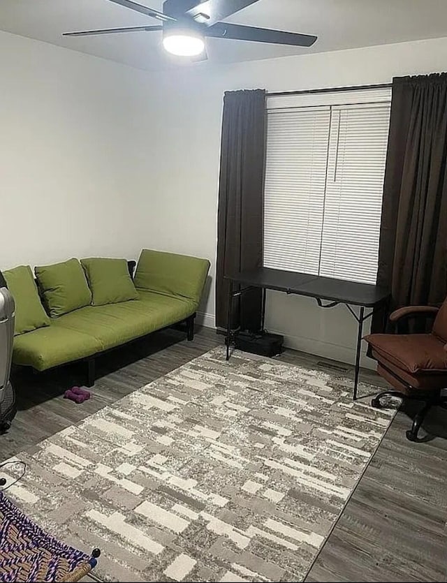 living room with a ceiling fan, baseboards, and wood finished floors