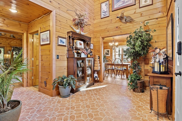 hallway with a notable chandelier, wood ceiling, and wooden walls