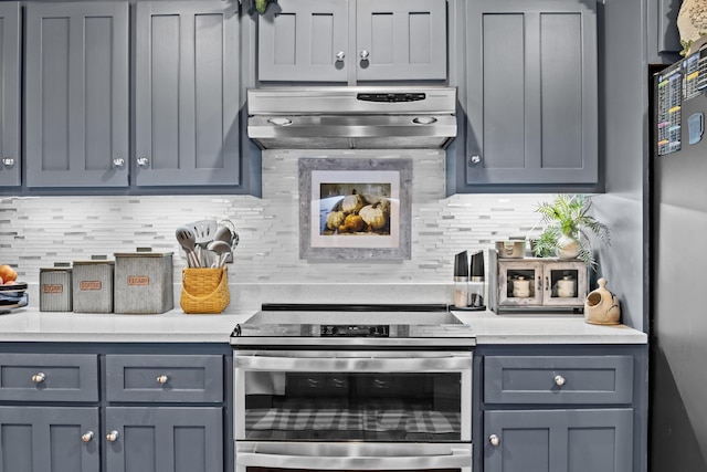 kitchen with appliances with stainless steel finishes, light countertops, backsplash, and wall chimney exhaust hood