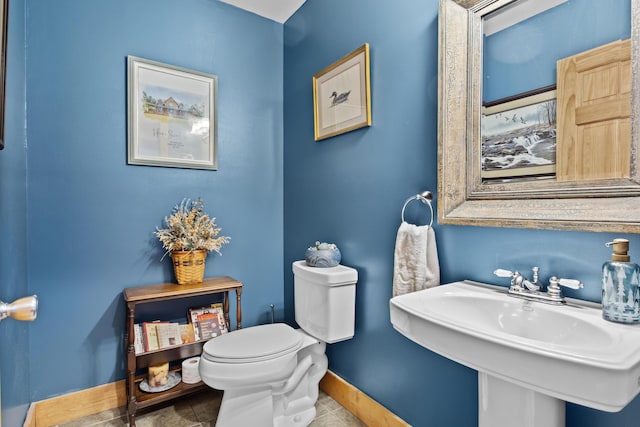 half bathroom with baseboards, a sink, toilet, and tile patterned floors