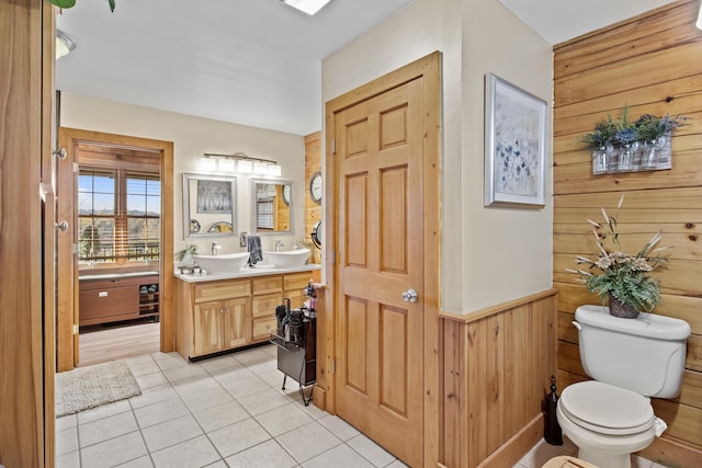 bathroom featuring vanity, tile patterned flooring, toilet, and wooden walls