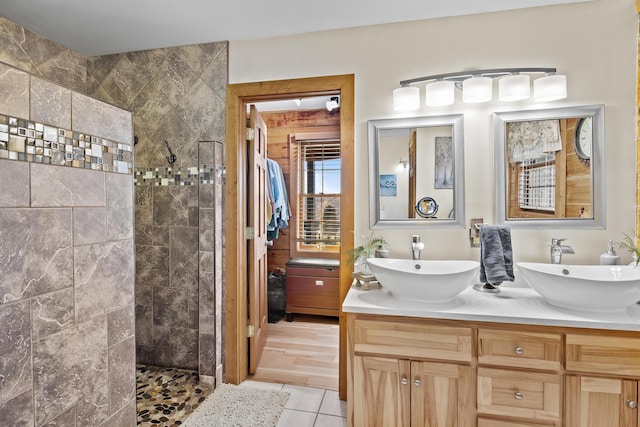 bathroom with a walk in shower, double vanity, a sink, and tile patterned floors