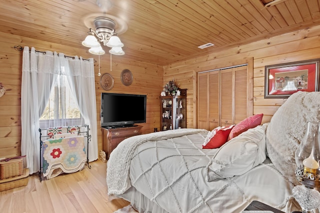 bedroom featuring a closet, visible vents, wood ceiling, wood walls, and wood finished floors