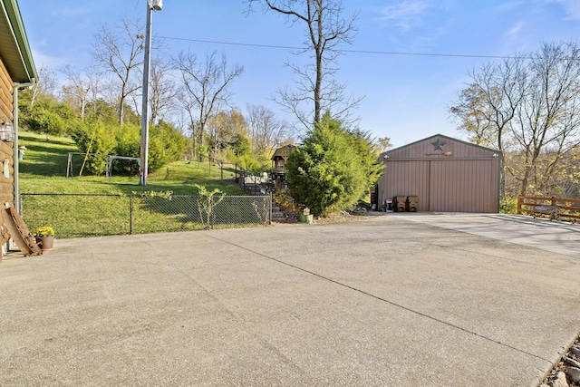 view of patio / terrace featuring an outbuilding, fence, and a garage