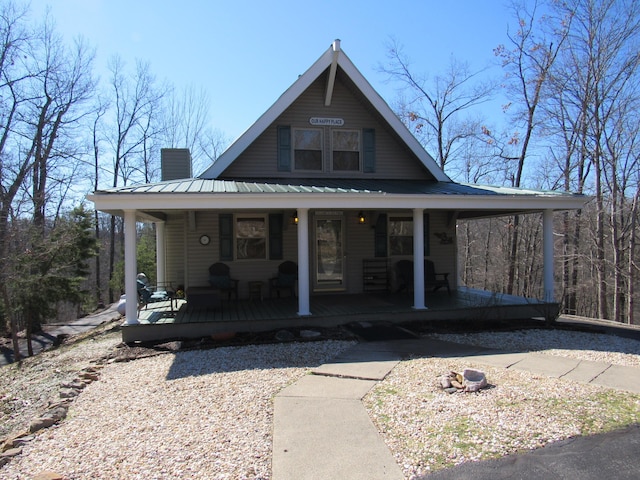 rustic home with a porch, metal roof, and a chimney