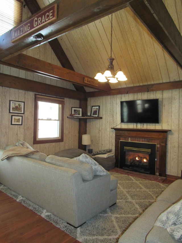 living room featuring lofted ceiling with beams, a fireplace with flush hearth, wood finished floors, wood walls, and a chandelier