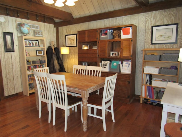 dining area with wood walls, beamed ceiling, and wood finished floors