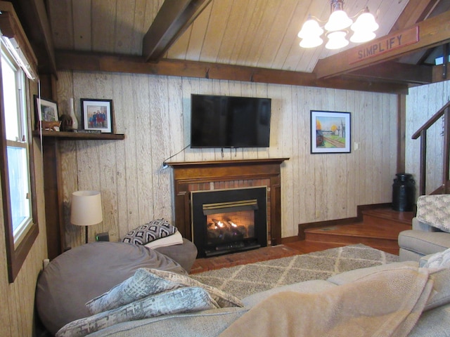 living area featuring stairway, a fireplace with flush hearth, a chandelier, wooden ceiling, and beamed ceiling