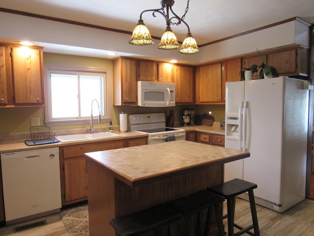 kitchen featuring white appliances, visible vents, a breakfast bar area, ornamental molding, and a sink