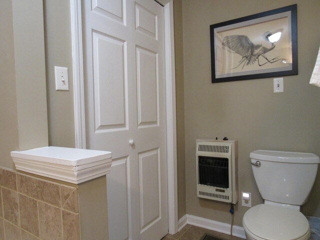 bathroom featuring heating unit, tile patterned flooring, toilet, and baseboards