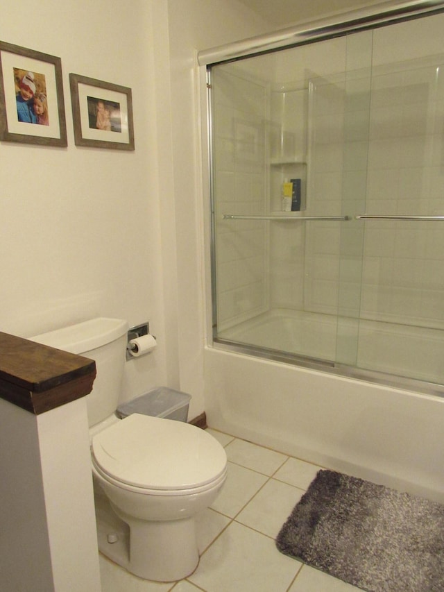 full bathroom featuring combined bath / shower with glass door, toilet, and tile patterned floors