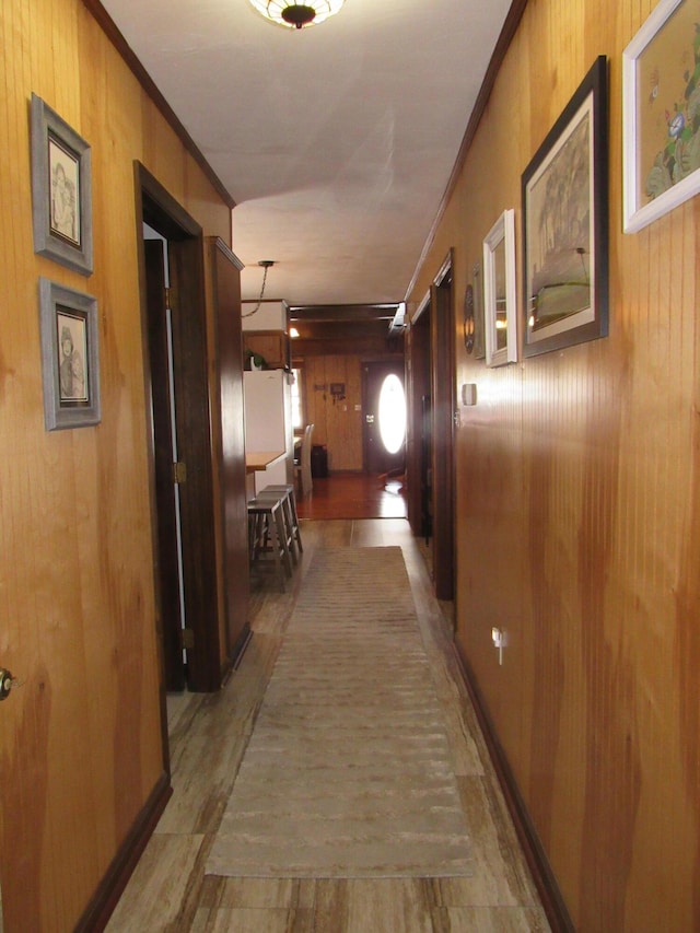 hall featuring crown molding, wood walls, and wood finished floors