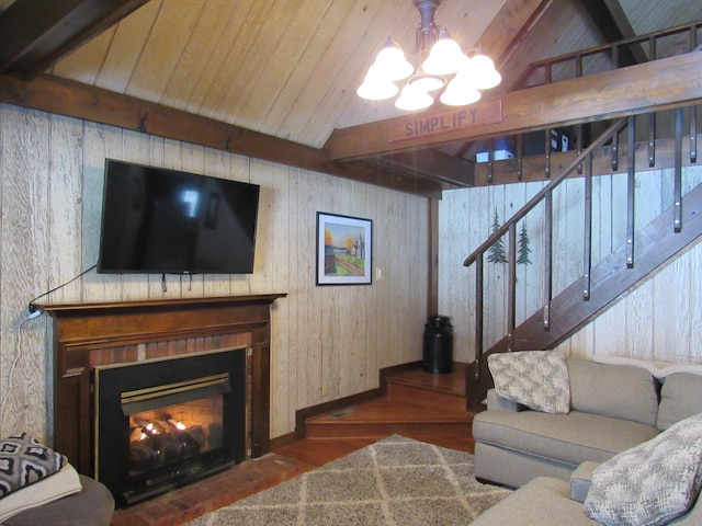 living area featuring wood ceiling, beamed ceiling, wood finished floors, a lit fireplace, and stairs