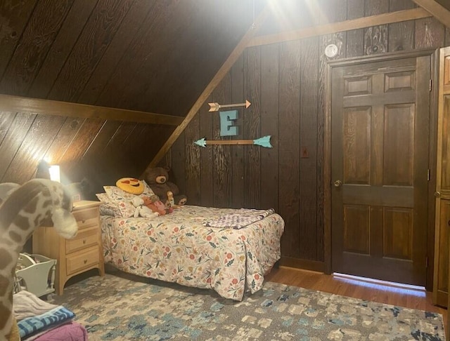 bedroom featuring vaulted ceiling, wooden walls, and wood finished floors