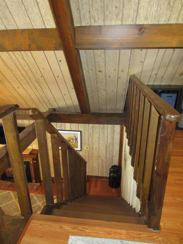 stairs featuring wooden ceiling, wood walls, beam ceiling, and wood finished floors