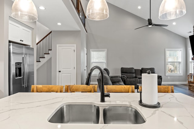 kitchen featuring light stone countertops, stainless steel fridge, and pendant lighting