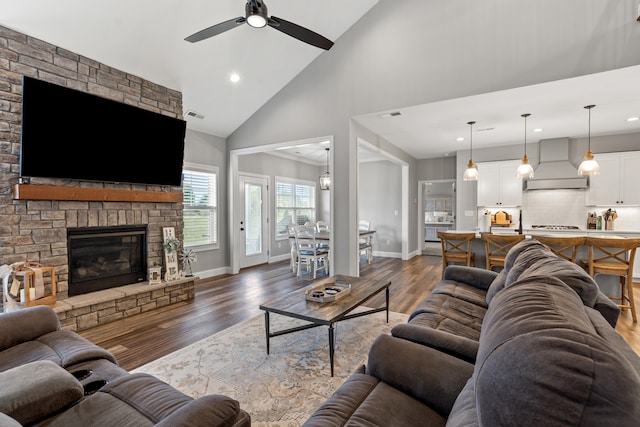 living area with a stone fireplace, dark wood-style flooring, baseboards, and visible vents