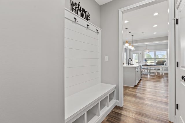 mudroom with wood finished floors, recessed lighting, and a sink