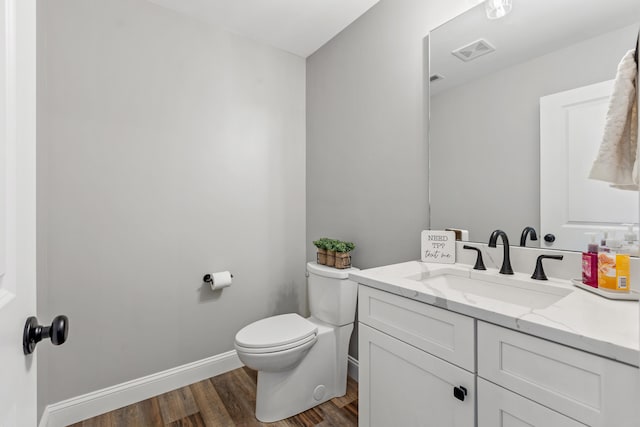 bathroom featuring baseboards, toilet, visible vents, vanity, and wood finished floors