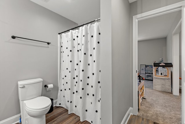 bathroom with toilet, baseboards, wood finished floors, and curtained shower