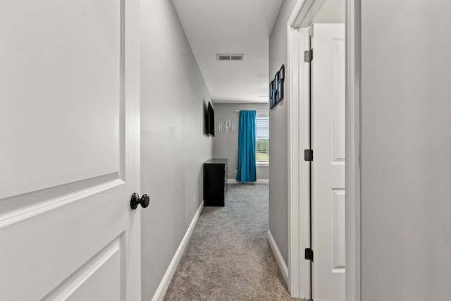 hall featuring light carpet, baseboards, and visible vents