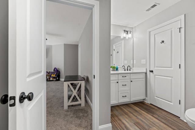 bathroom with toilet, baseboards, vanity, wood finished floors, and visible vents