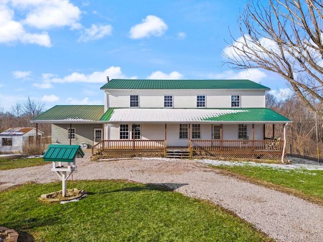 view of front of home with a porch, a front yard, metal roof, and driveway