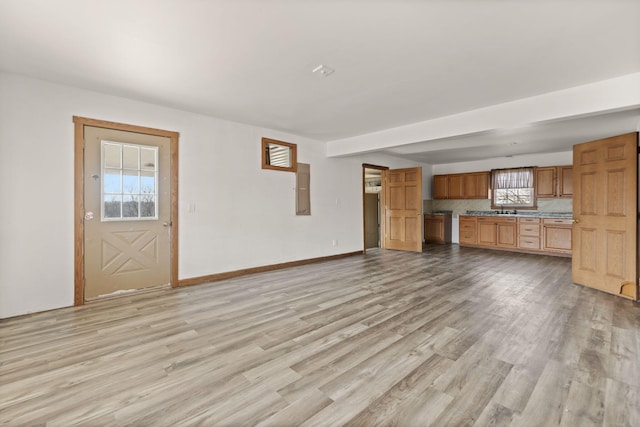 unfurnished living room featuring baseboards and light wood finished floors