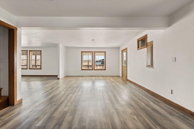 unfurnished living room featuring baseboards, a wealth of natural light, and wood finished floors