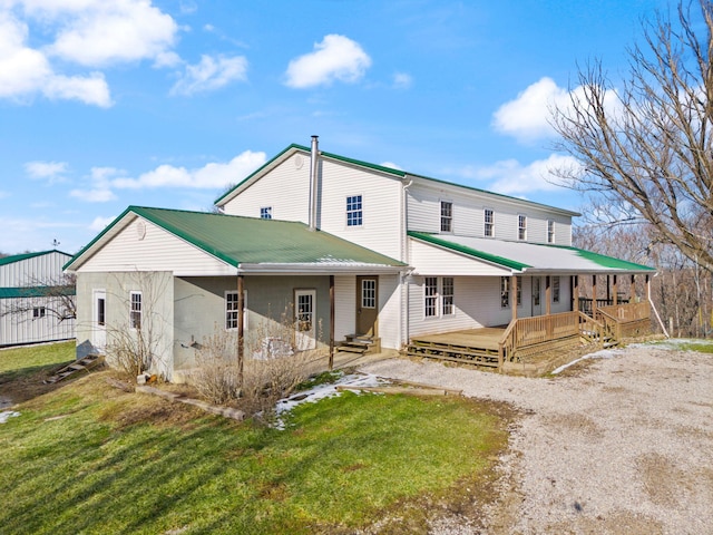 view of front facade featuring dirt driveway, metal roof, and a front lawn