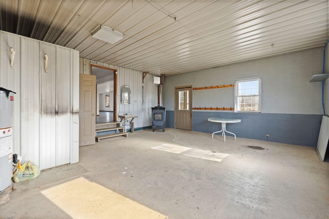 misc room featuring a wood stove, unfinished concrete floors, and concrete block wall