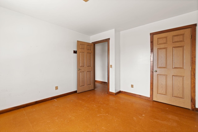 unfurnished bedroom featuring concrete flooring and baseboards