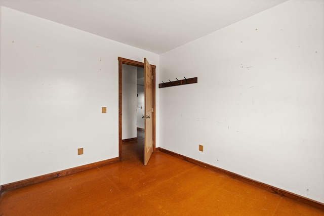 spare room featuring finished concrete floors and baseboards