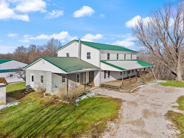 back of property with metal roof, driveway, and a yard