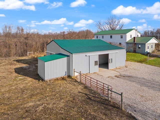 view of pole building featuring driveway and fence