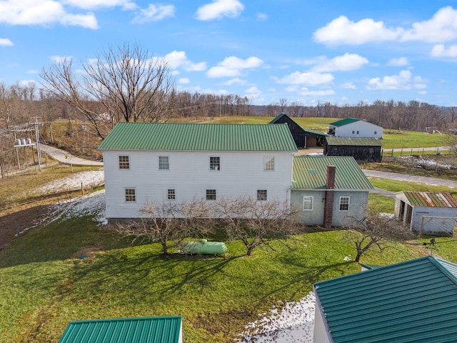 back of property with metal roof and a yard