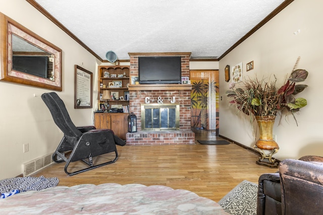 living room with ornamental molding, visible vents, a textured ceiling, and wood finished floors