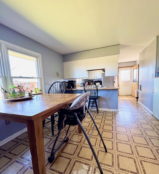 dining space featuring light floors and baseboards