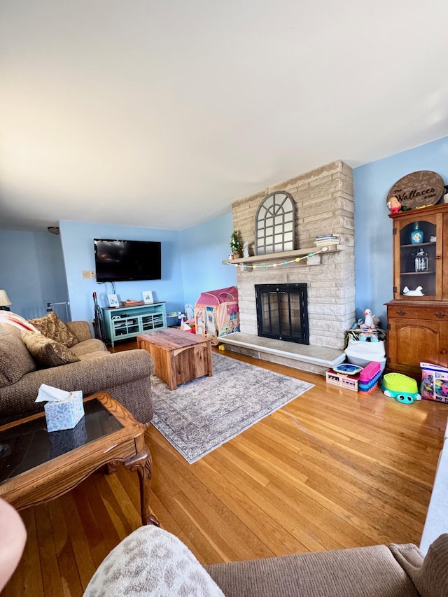 living area with hardwood / wood-style floors and a stone fireplace