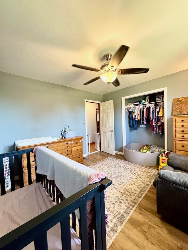 bedroom featuring a closet, ceiling fan, baseboards, and wood finished floors