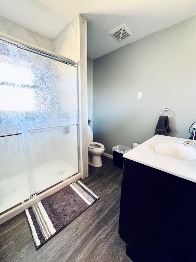 full bath with toilet, wood finished floors, vanity, visible vents, and a stall shower