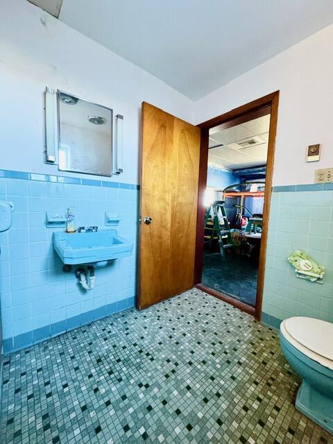 bathroom with wainscoting, a sink, tile walls, and toilet