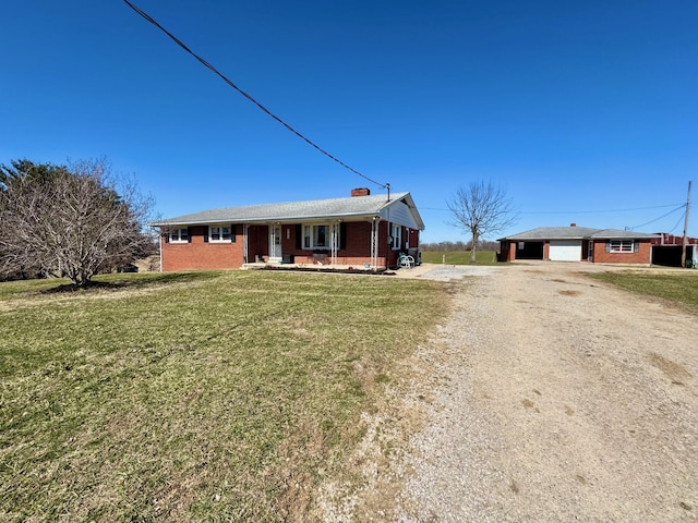 ranch-style home with brick siding, a garage, an outdoor structure, driveway, and a front lawn