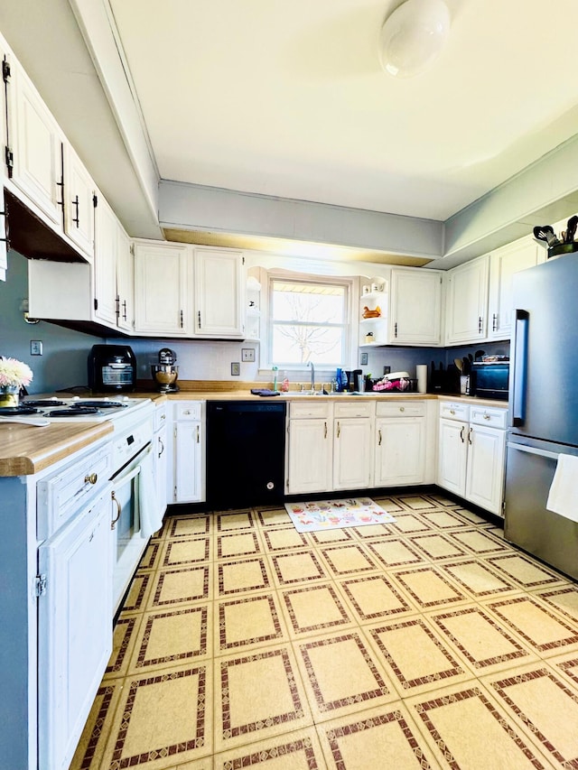 kitchen with black dishwasher, open shelves, freestanding refrigerator, white cabinetry, and a sink