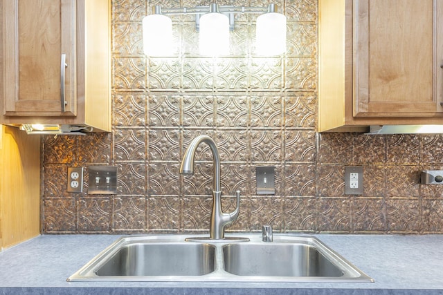 kitchen with brown cabinetry, a sink, and backsplash